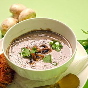 Delicious homemade mushroom soup garnished with parsley, served with crispy bread slices.