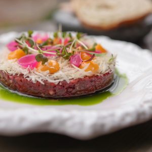 Delicious gourmet tartare elegantly presented on a white plate with vibrant garnishes.